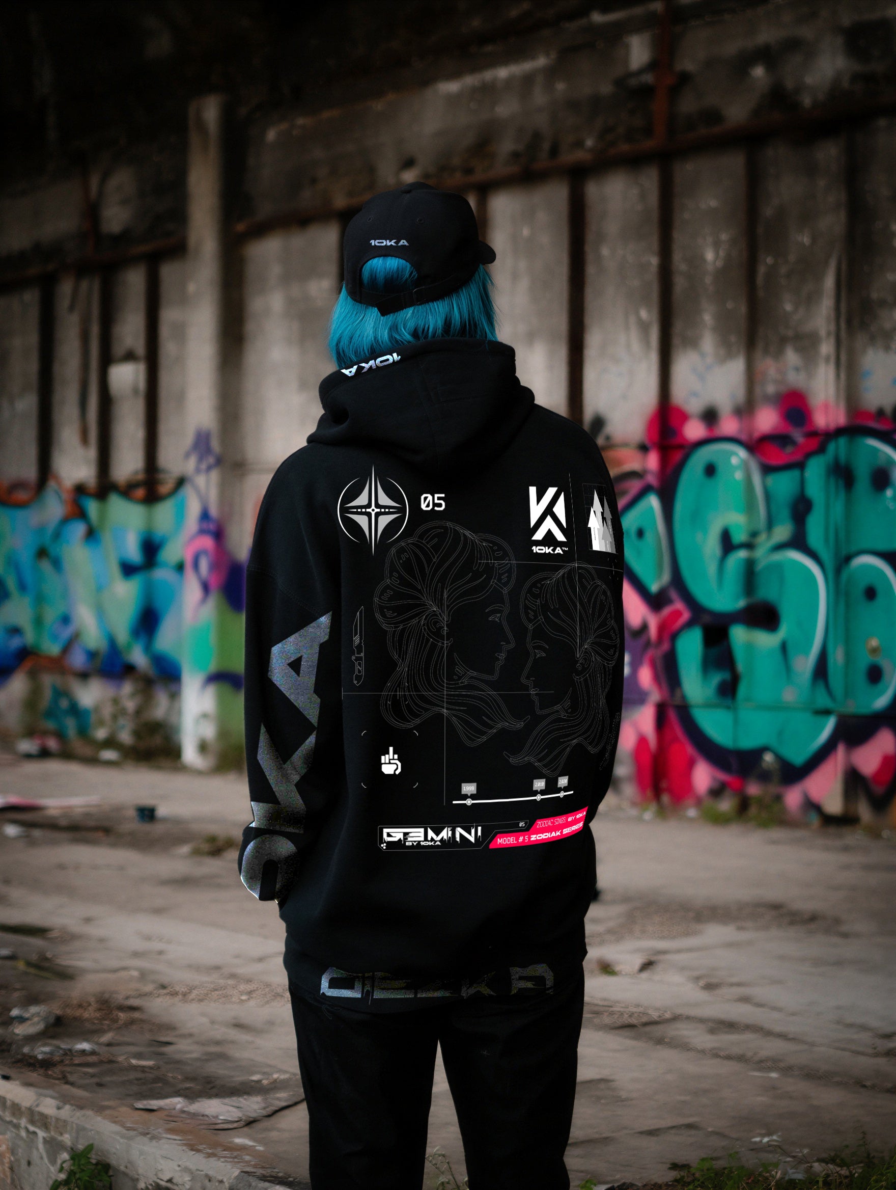 Model wearing the Zodiac Hoodie Gemini by 10KA in an urban setting, back view, showcasing dynamic futuristic graphics inspired by adaptability and communication.
